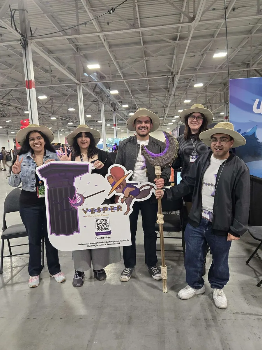 Five members of the team at the Vesper booth, holding a cardboard cut-out of Vesper